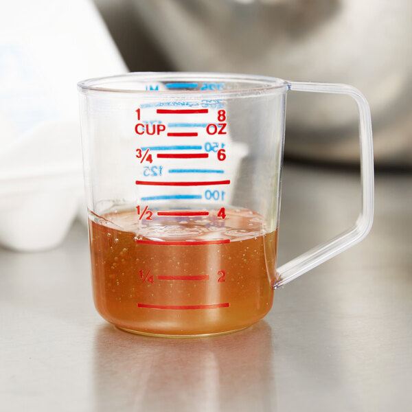 A clear Rubbermaid measuring cup with brown liquid inside.