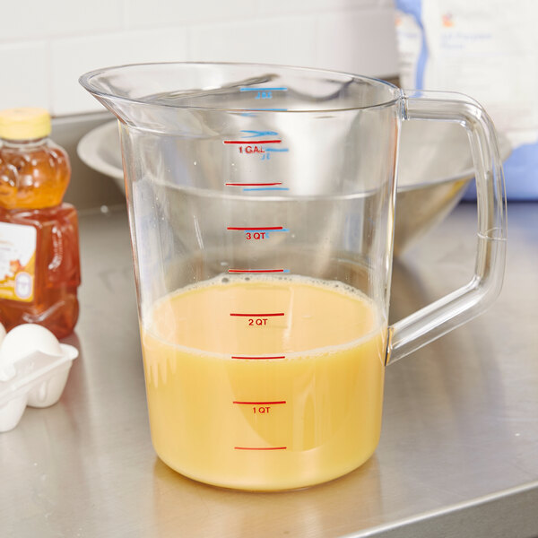 A Rubbermaid clear plastic measuring cup with yellow liquid in it.