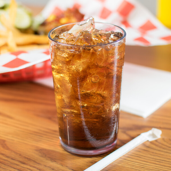 A Cambro clear plastic tumbler filled with ice tea on a table.