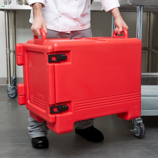 A man holding a red Cambro front-loading insulated food pan carrier.