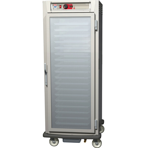 A white holding cabinet with clear glass doors on wheels.