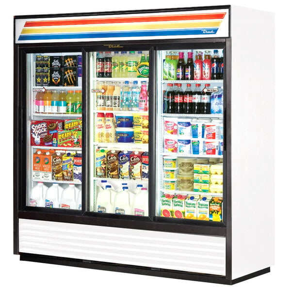 A white True refrigerated glass door merchandiser with LED lighting and shelves full of beverages.