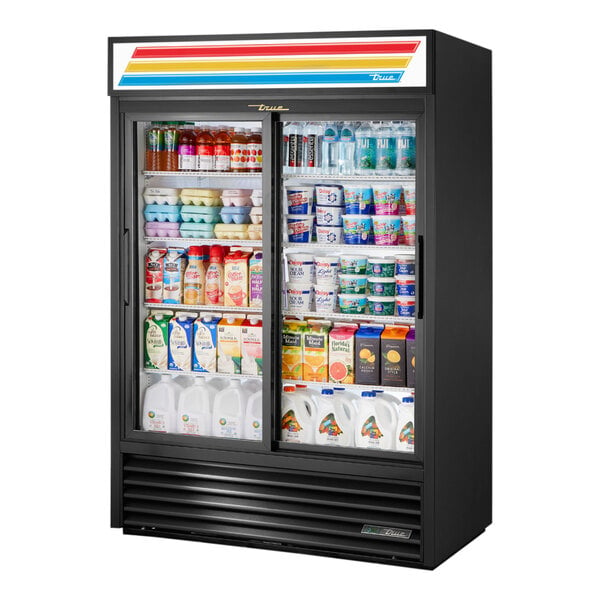 A black True refrigerated merchandiser with a glass door displaying a variety of beverages.