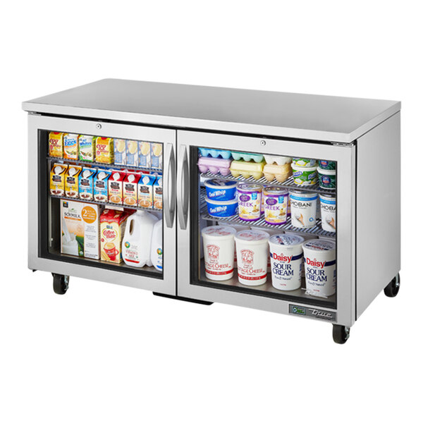 A True undercounter refrigerator with glass doors full of dairy products.