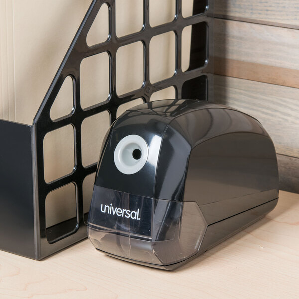 A black Universal electric pencil sharpener on a wood surface.
