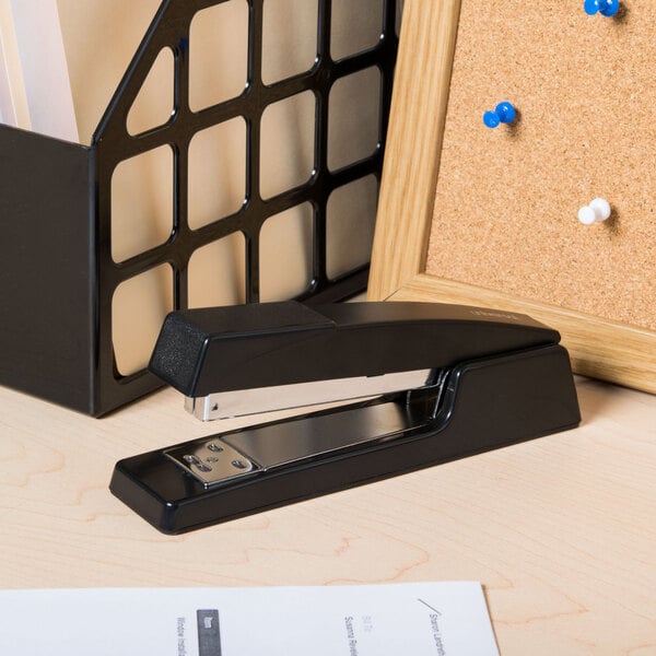 A Universal black classic stapler on a desk next to a piece of paper.