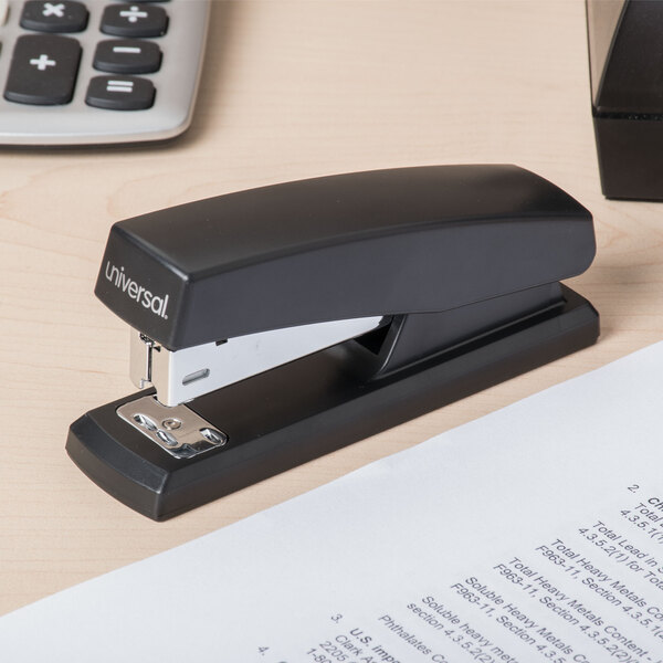 A Universal black half strip desktop stapler on a desk.