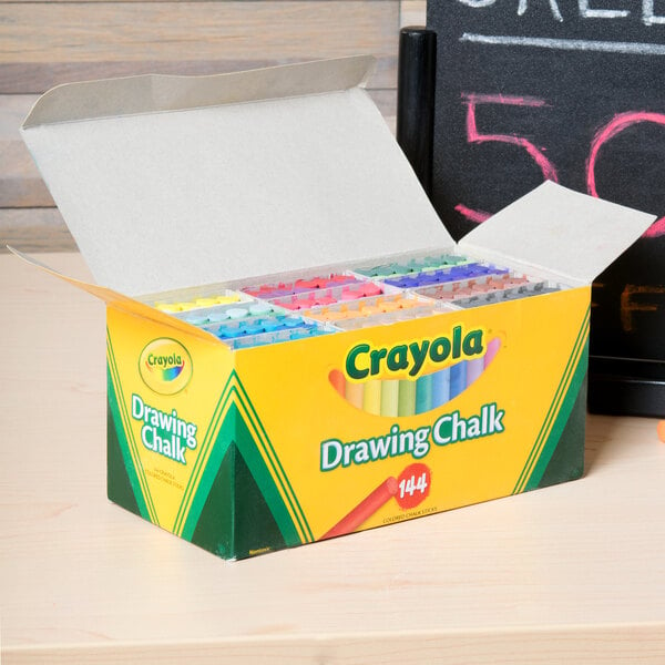 A box of Crayola drawing chalk on a table next to a box of crayons.