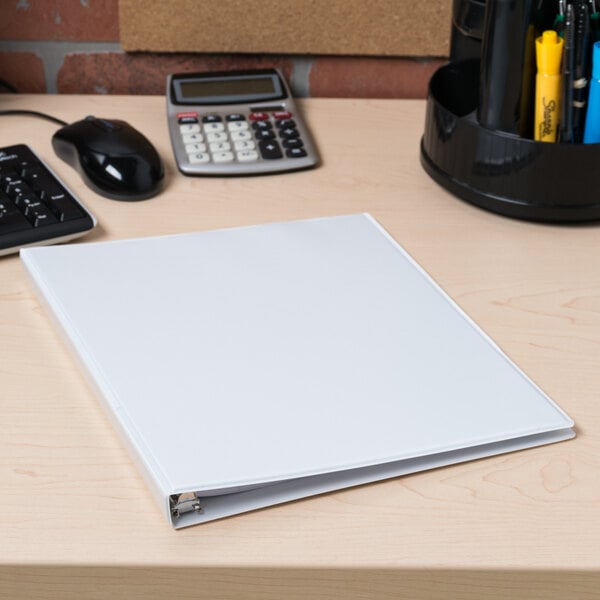 A white Avery Economy View binder on a wood desk.