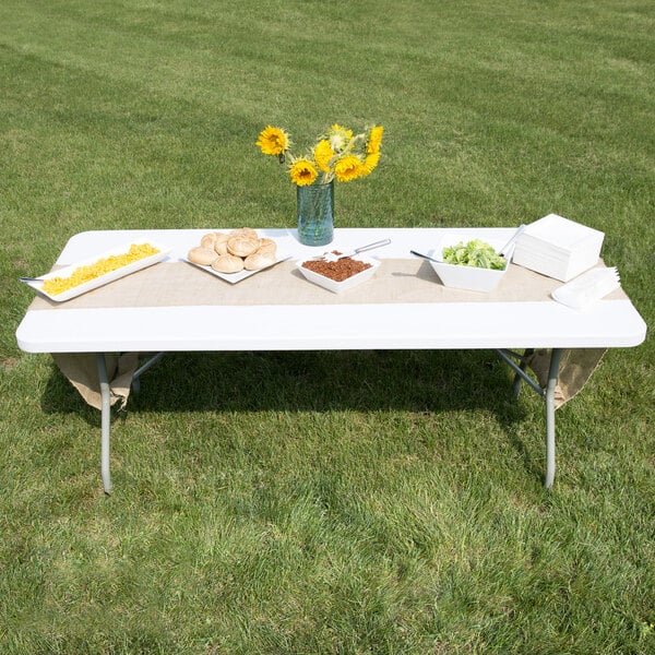 A Lancaster Table & Seating white rectangular plastic folding table with food on it.