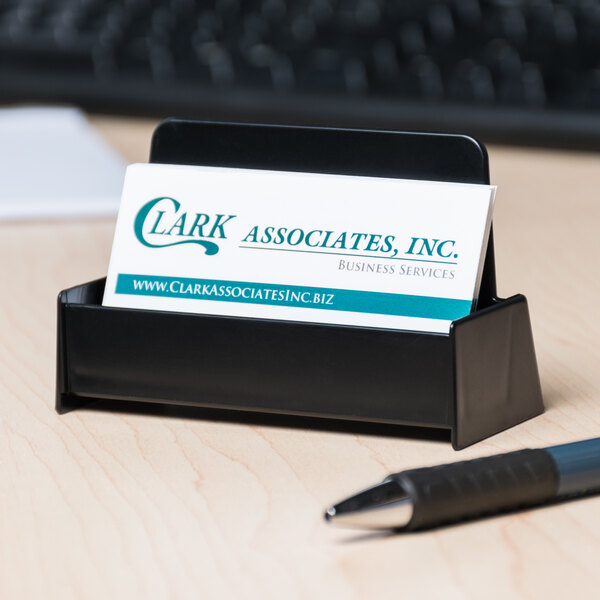 A black Universal business card holder sitting on top of a desk with a business card inside.