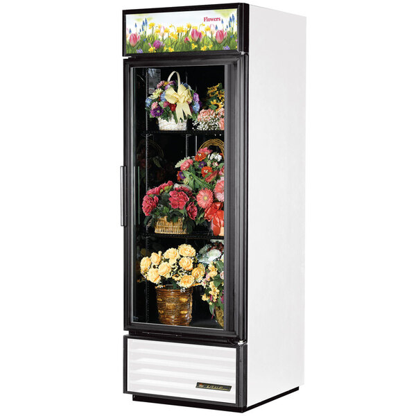 A white True refrigerated glass door floral case with flowers inside.