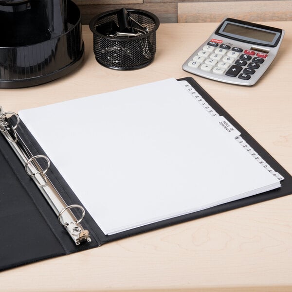 A binder with Avery Premium Table of Contents Dividers on a table with a calculator and paper.