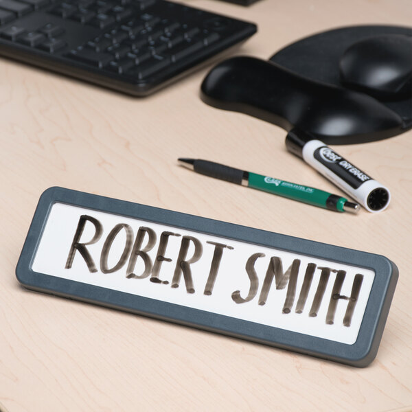 A white Universal plastic cubicle nameplate with a charcoal frame and the name Robert Smith written on it.