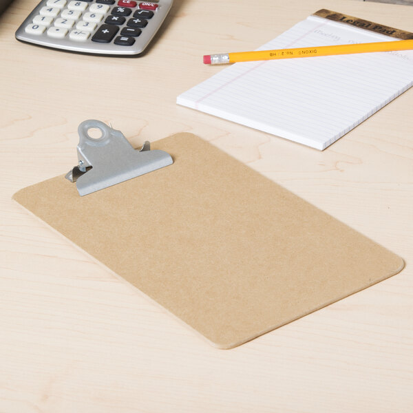 A Universal brown hardboard clipboard holding a paper and a calculator on a desk.