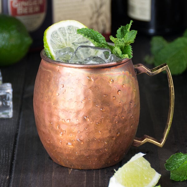 An American Metalcraft hammered antique copper Moscow Mule mug filled with ice and lime slices.