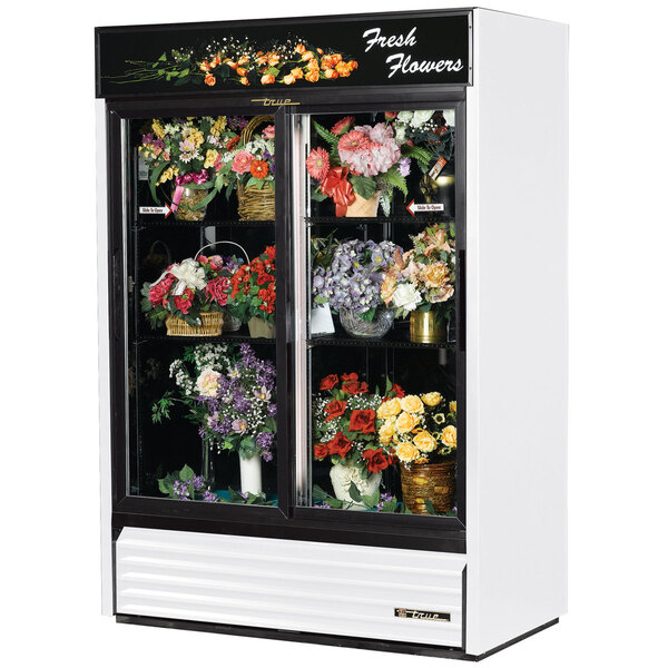 A True white refrigerated sliding glass floral case with flowers inside.