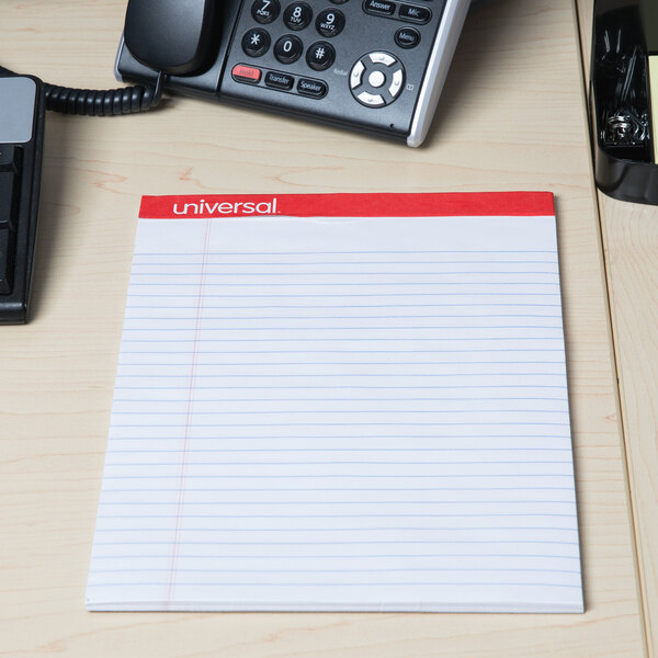 A telephone and Universal Legal Ruled Writing Pad on a desk.