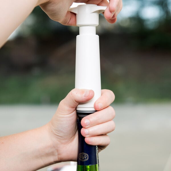 A hand using the Vacu Vin White Wine Saver to seal a bottle of wine.