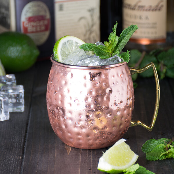 An American Metalcraft hammered copper Moscow Mule mug with ice and limes.