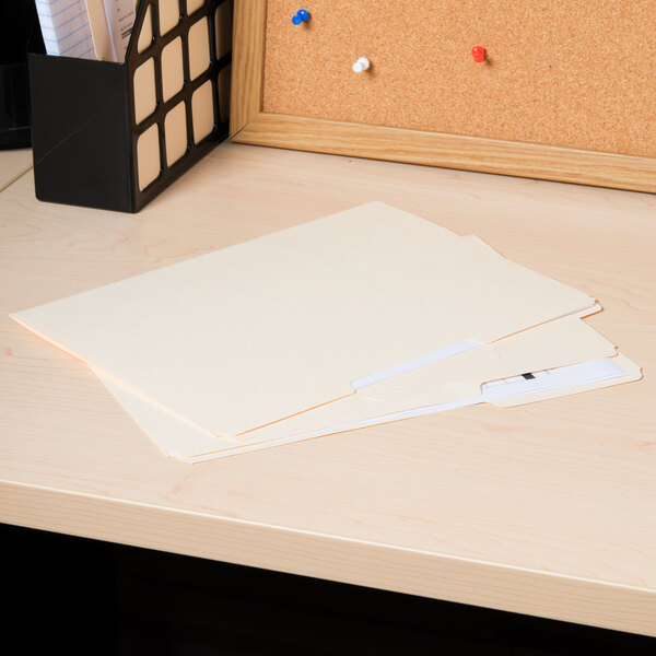 A Universal manila file folder with 1/3 cut tabs on a desk with papers.