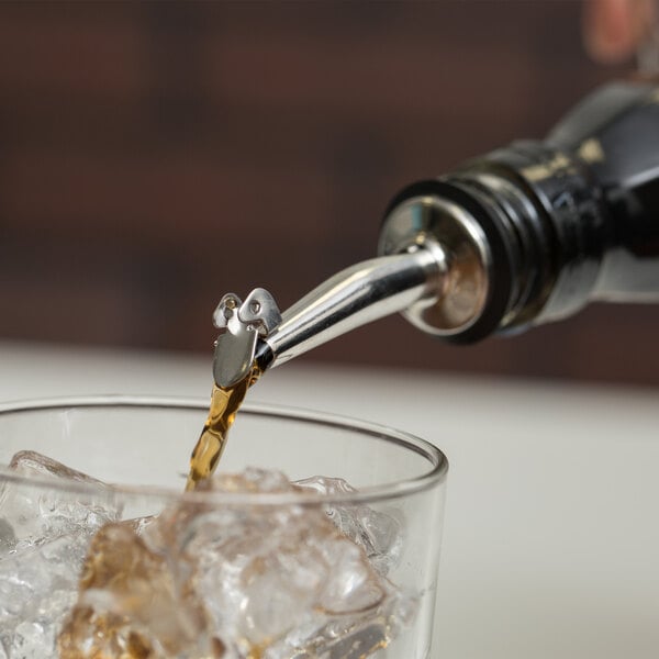 An Acopa stainless steel liquor pourer pouring a drink into a glass.