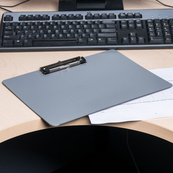A Universal plastic landscape clipboard on a desk with a pen on top.