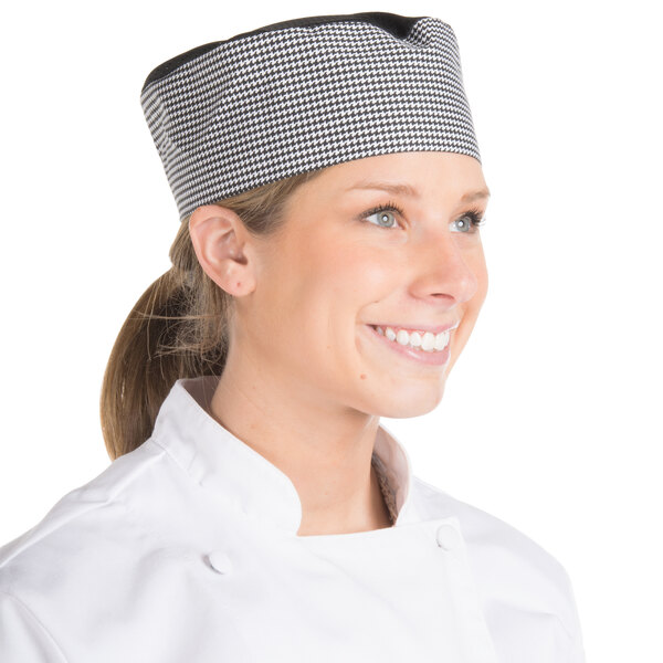 A woman wearing a Chef Revival houndstooth baker's hat with a black and white checkered design.