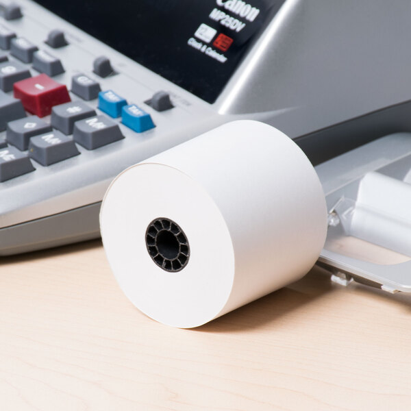 A roll of paper on a desk next to a Universal Office calculator.