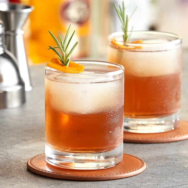 Two Acopa old fashioned glasses of whiskey with rosemary garnish.