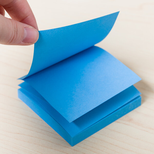 A hand holding a Universal bright blue fan-folded pop-up note.
