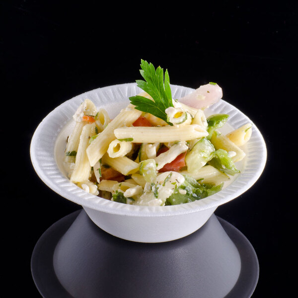 A Dart white foam bowl filled with pasta salad and garnished with leafy greens.