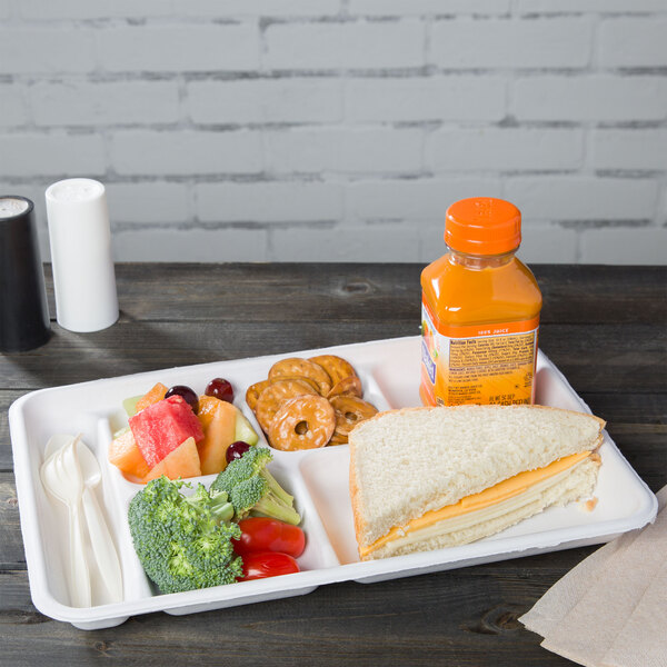 A white Huhtamaki Chinet cafeteria tray with food including a sandwich, fruit, and a bottle of juice.