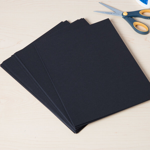 A stack of Astrobrights Eclipse Black cardstock paper next to scissors.