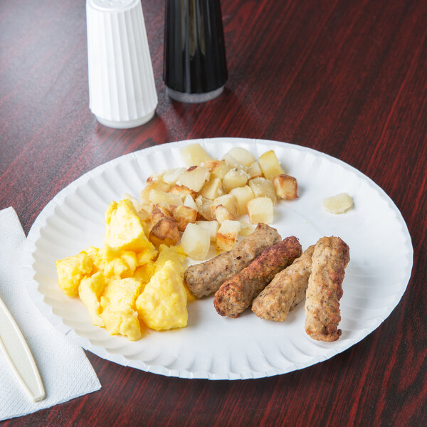 A white 9" uncoated paper plate with breakfast food on a table.