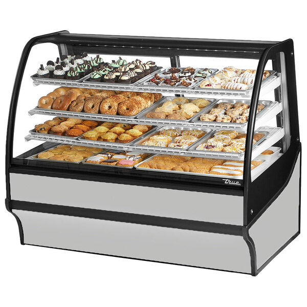 A True curved glass stainless steel dry bakery display case on a counter with trays of pastries.