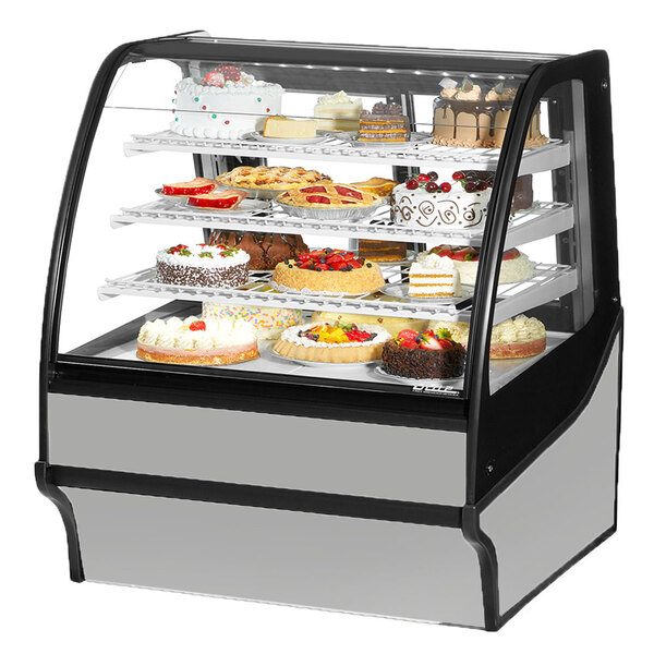 A True refrigerated bakery display case with cakes on it.