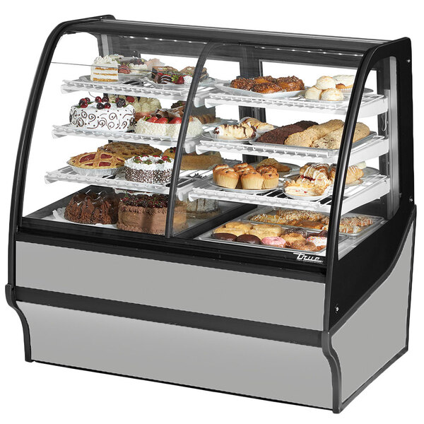 A True dual service refrigerated bakery display case with food on it including cakes and pastries.