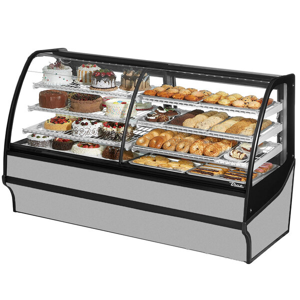 A True curved glass stainless steel dual service refrigerated bakery display case full of cakes and pastries.