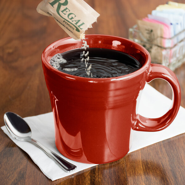 A Scarlet Fiesta tapered china mug filled with coffee on a table with a spoon.
