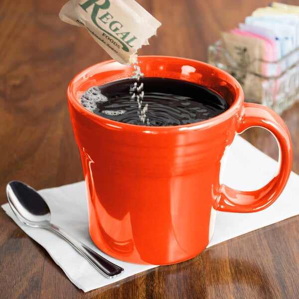 A person pouring coffee into a red Fiesta mug.