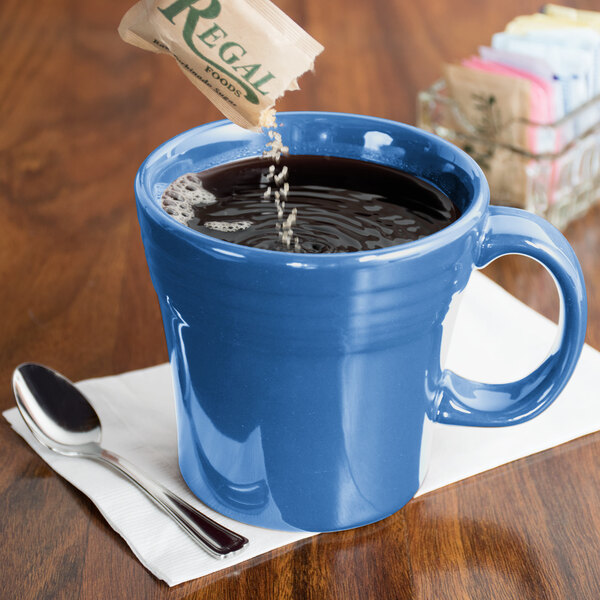 A blue Fiesta china mug on a counter with a spoon in it.