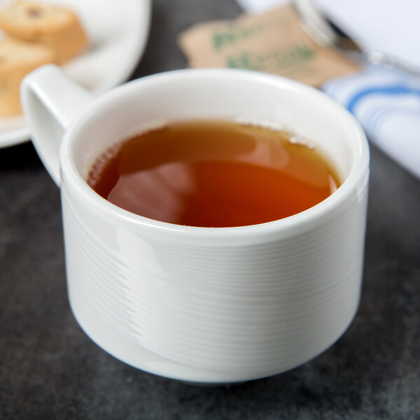 A white Royal Rideau porcelain cup filled with tea on a table.