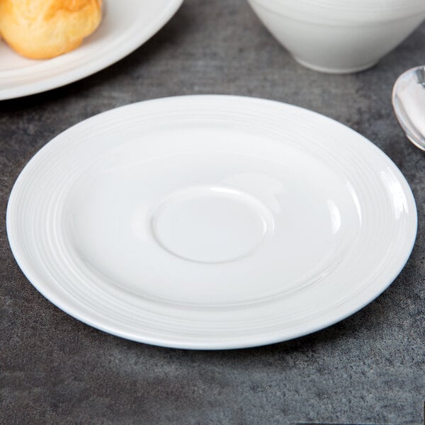 A white Royal Rideau porcelain saucer with a spoon on it.