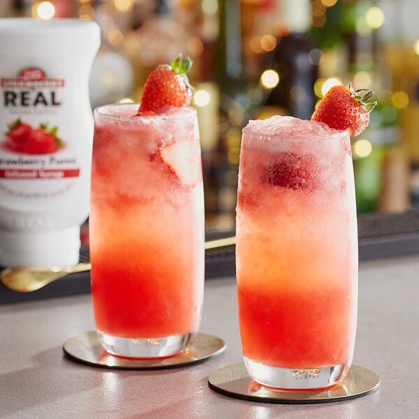 Two glasses of Real strawberry drink garnished with strawberries.