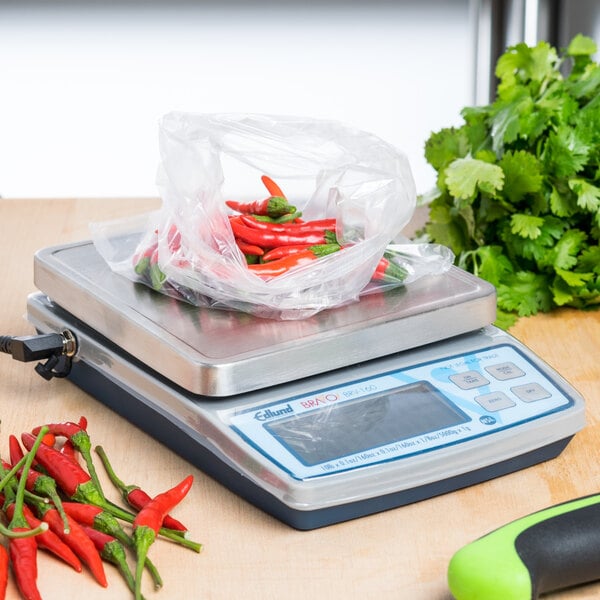 An Edlund digital portion scale with a bag of red peppers on top.