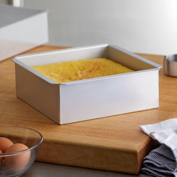 An Ateco square aluminum cake pan with a yellow square cake inside.