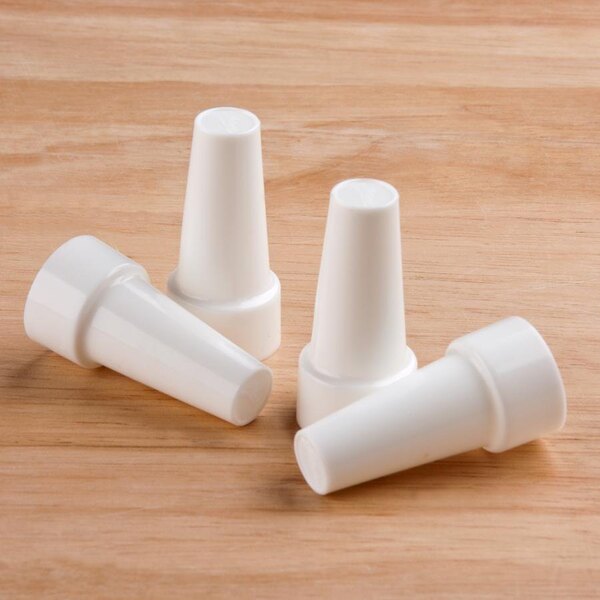 Three white plastic Ateco piping tip covers on a wood surface.