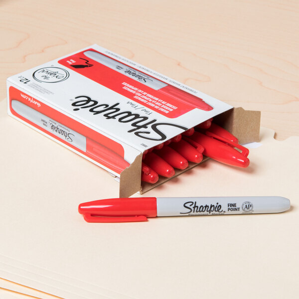 A box of red Sharpie markers with white writing on a table.