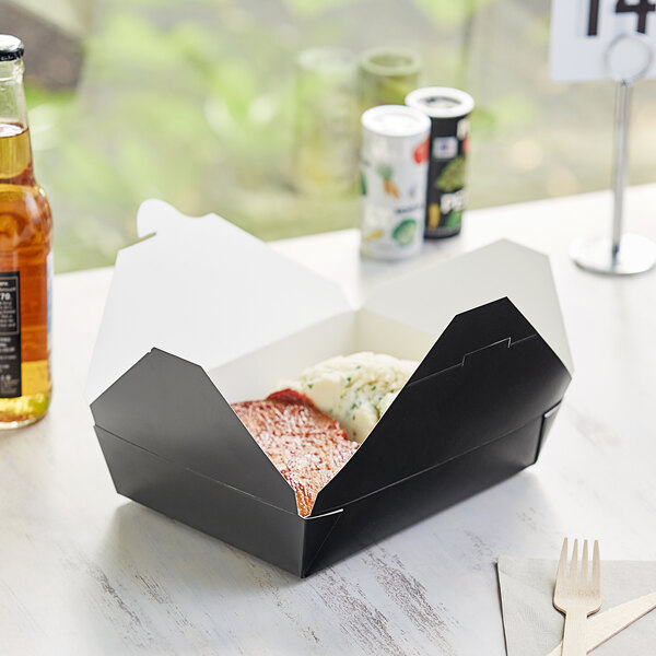 A black Choice paper take-out box with food in it.